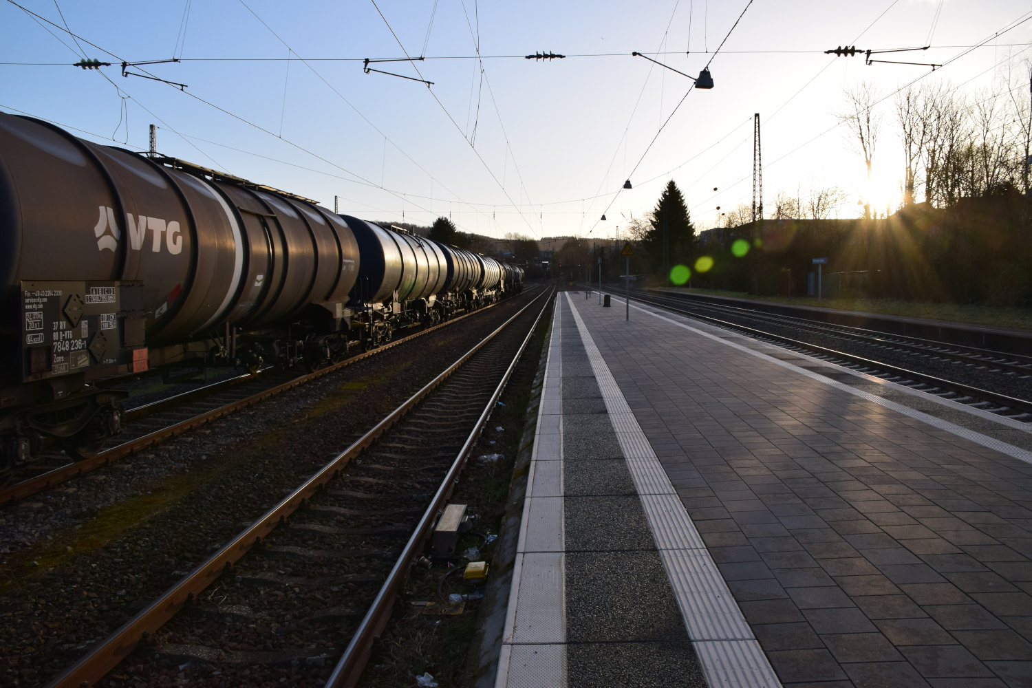 Ein Bahnsteig Wilferdingen-Singen mit Gleisen auf den ein Güterwagon steht